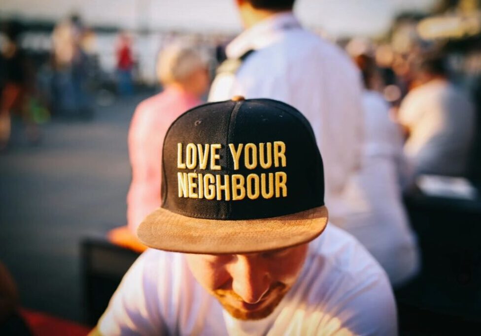 A man wearing a hat that says love your neighbour.